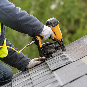 photo of a man on roof installing shingles